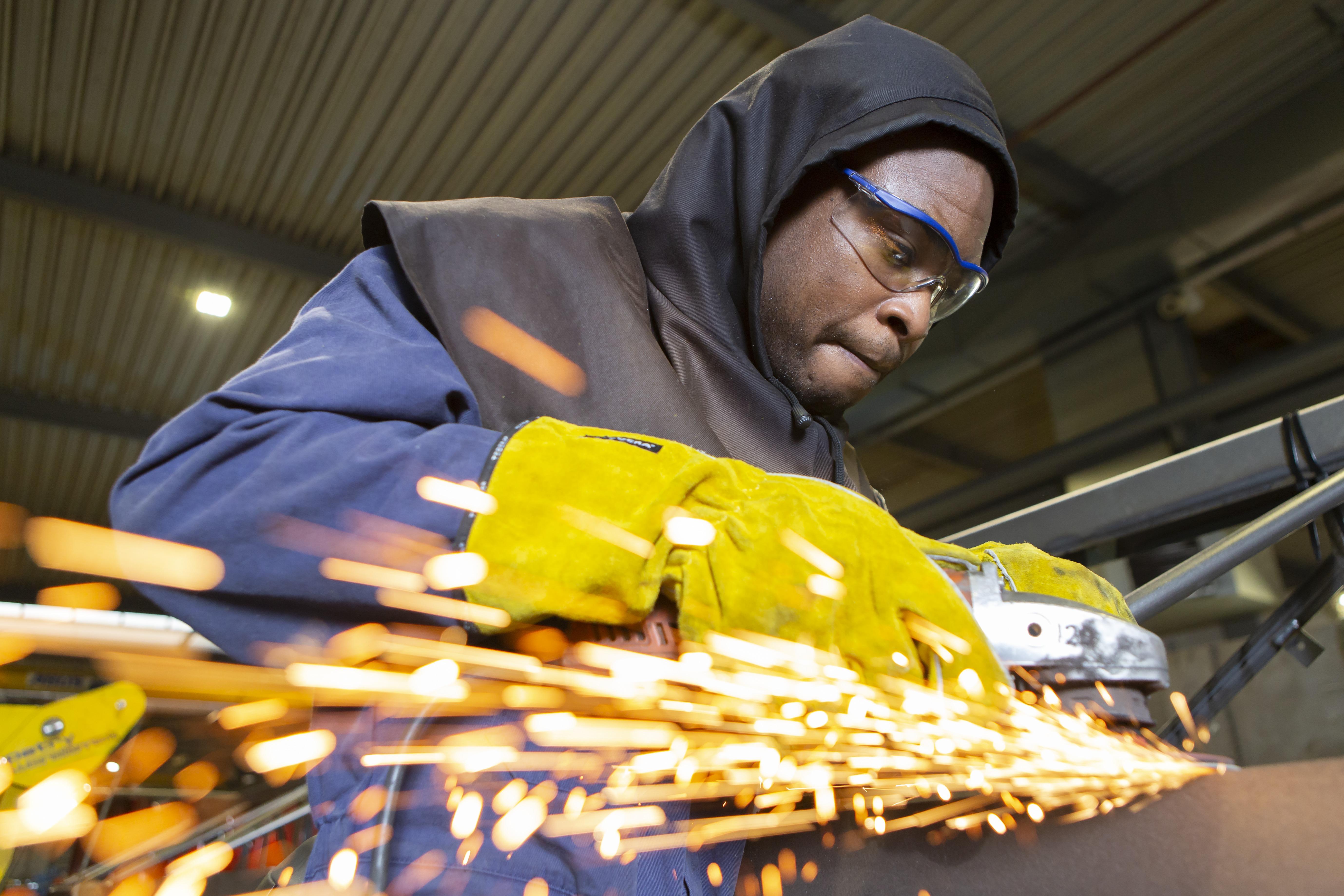 Een lasser aan het werk met beschermende veiligheidsbril en handschoenen.